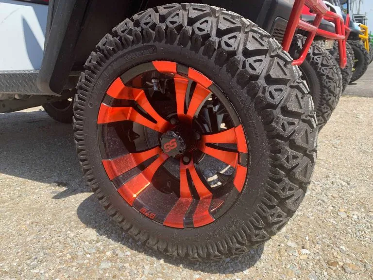 Close-up of a lifted golf cart's orange and black wheel and off-road tire